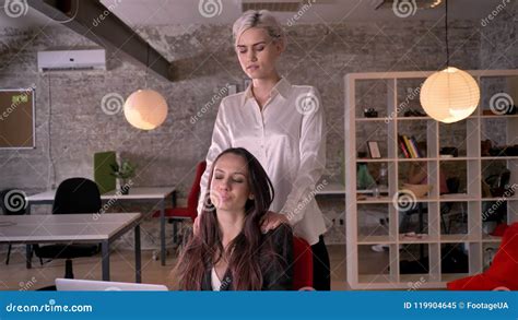 Young blonde lesbian massaging woman in modern office during。